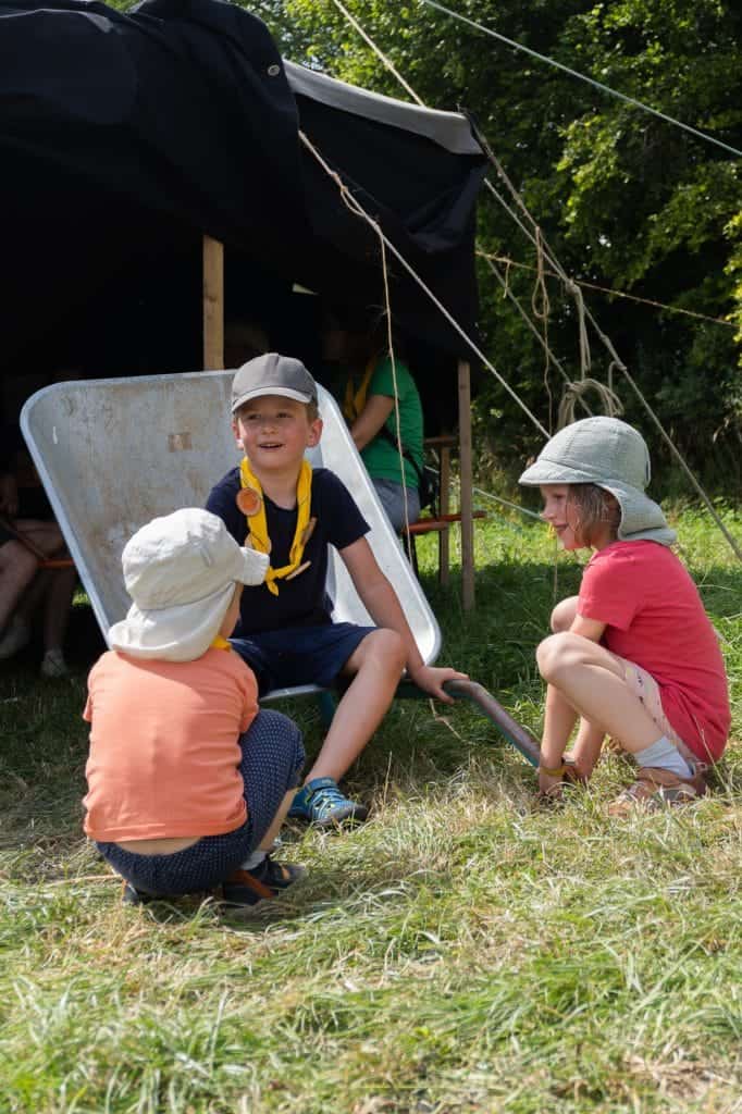 Kinder sitzen um eine Schubkarre herum